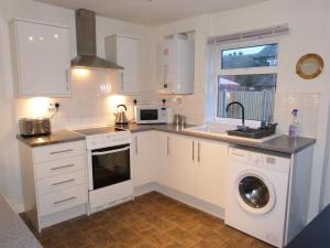 cocina con armarios blancos, lavadora y secadora en Marina Cottage, Newark, en Newark-on-Trent