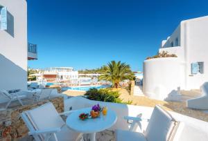 a balcony with white chairs and a table and a pool at Chora Resort Hotel & Spa in Chora Folegandros