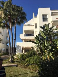un edificio alto y blanco con palmeras delante en Miraflores Golf Gardens II Luxe Appartement at Riviera del Sol, en Mijas Costa