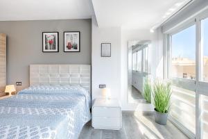 Dormitorio blanco con cama y ventana grande en Estepona Real Apartamentos, en Estepona