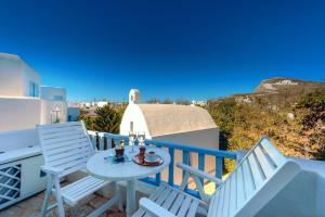a balcony with white chairs and a table and a view at Chora Resort Hotel & Spa in Chora Folegandros