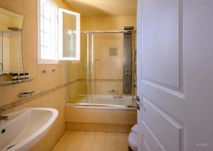 a bathroom with a shower and a tub and a sink at Chora Resort Hotel & Spa in Chora Folegandros