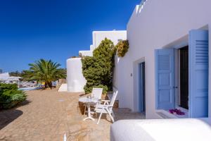 a white building with a table and chairs on a beach at Chora Resort Hotel & Spa in Chora Folegandros