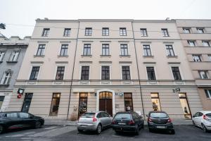 Un gran edificio blanco con coches aparcados delante. en Boho Lofts - LoftAffair, en Cracovia