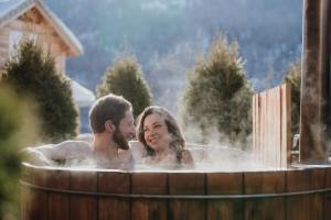 Un uomo e una donna seduti in una vasca idromassaggio di Résidence Sunêlia Les Logis d'Orres a Les Orres