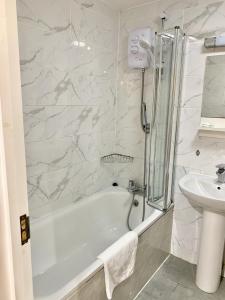 ein weißes Badezimmer mit einer Badewanne und einem Waschbecken in der Unterkunft Britannia Inn Hotel in Ilford