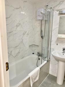a white bathroom with a tub and a sink at Britannia Inn Hotel in Ilford