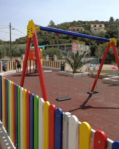 a colorful fence with swings in a playground at Apartments Pecotić in Brna