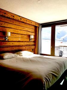 een slaapkamer met een bed met een houten muur bij Alberta Hotel & Spa in Val Thorens