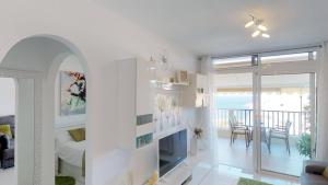 a white living room with a television and a balcony at Amadores Sunset Suite in Amadores