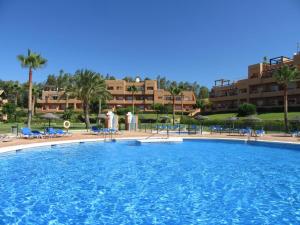 a large swimming pool with blue chairs and buildings at CASARES appart 2 ch dans parc tropical avec vue sur mer, montagne et piscine in Casares