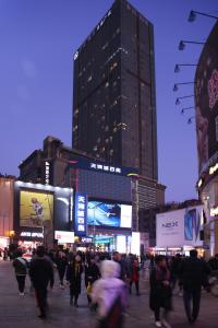 una multitud de personas caminando por una calle de la ciudad por la noche en Guangzhou Ba Dun Hotel - Beijing Road, en Guangzhou
