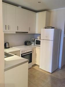 eine Küche mit weißen Schränken und einem weißen Kühlschrank in der Unterkunft Seafront apartment ΙΙ in Kiveri, near Nafplion. in Kiveri