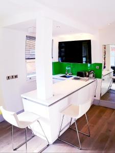 eine Küche mit einer weißen Theke und 2 weißen Stühlen in der Unterkunft Lake Street Studios in Oxford