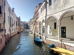 ein Kanal zwischen zwei Gebäuden mit Booten in der Unterkunft San Giorgio degli Schiavoni in Venedig