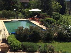 una piscina con ombrellone in un cortile di Grand Vue Vert a Roubert