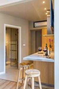 a kitchen with two stools and a counter with wine glasses at One Love Metropolitan Gardens Studio II in Bucharest