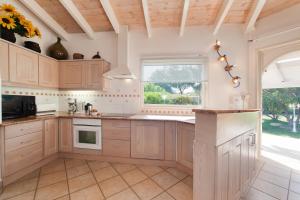 a large kitchen with wooden cabinets and a window at Villa Le Lagon - Vision Luxe in Bonifacio