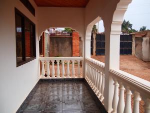 a porch of a house with a white railing at Kampala Kiwatule Comfy Holiday Home in Kampala
