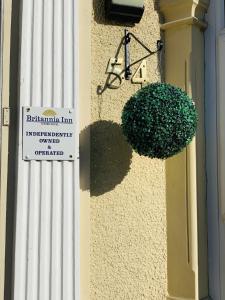 a green bush on the side of a building with a sign at Britannia Inn Hotel in Ilford