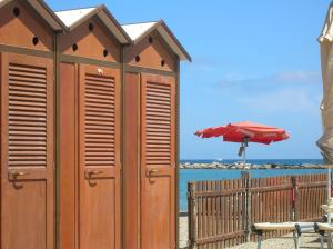 a wooden building on a beach with an umbrella at Hotel Delle Rose in San Bartolomeo al Mare