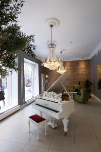 a white piano in a room with a chandelier at Hotell Hjalmar in Örebro