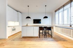 a kitchen with white cabinets and a table with stools at Center Apartment, Vilnius, Old Town in Vilnius