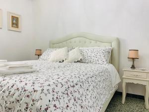 a bedroom with a white bed with a floral bedspread at Temporary House Oberdan in Bologna