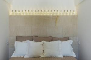 a bunch of wine bottles above a bed with pillows at Trapetum-Salento domus in Cursi