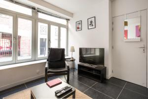 a living room with a chair and a television at Charmant appartement au coeur du Vieux Lille in Lille