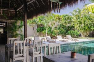 een patio met stoelen, een tafel en een zwembad bij Villas H2O in Tulum