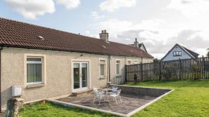 a patio with two chairs and a table in a yard at Pippin, Tranquil Scottish Cottage with Hot Tub in Airdrie