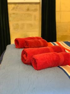 a group of red towels laying on a bed at St Elias Apartment in St. Julianʼs