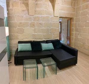 a black leather couch in a living room with two glass tables at St Elias Apartment in St. Julianʼs