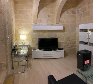 a living room with a tv and a stone wall at St Elias Apartment in St. Julianʼs