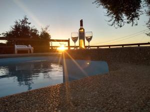 una botella de vino y dos copas de vino junto a una piscina en Cabañas Quillay, en Constitución