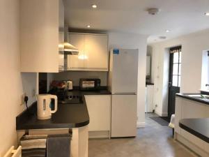 a kitchen with white cabinets and a black counter top at 200m To Botanical Garden 3 Bedroom Victoria House in Cambridge