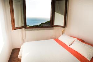 a bedroom with a bed and a window with the ocean at Arromaniu in Nebida