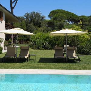 two chairs and umbrellas next to a swimming pool at Arli Hotel Hideaway Punta Ala - Adults Only in Punta Ala