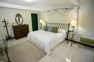 sypialnia z białym łóżkiem i lustrem w obiekcie Bomtempo II Chales by Castelo Itaipava w mieście Itaipava