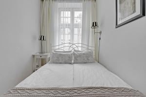a bed in a white bedroom with a window at BE IN GDANSK Apartments - IN THE HEART OF THE OLD TOWN - Mariacka 31/33 in Gdańsk