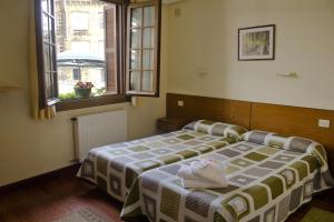 1 dormitorio con 2 camas y 2 ventanas en Pension Getariano, en Getaria