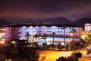 um grande edifício branco com palmeiras à noite em Pashas Princess by Werde Hotels - Adult Only em Kemer