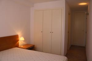 a bedroom with a bed and a cabinet and a lamp at Apartamento moderno en el centro de moraira in Moraira