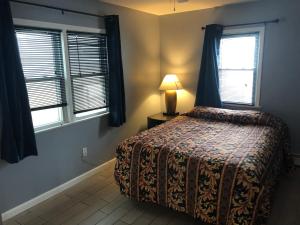 a bedroom with a bed and two windows and a lamp at Newly Renovated 2 Bedroom House in Seaside Heights