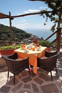 einen Tisch und Stühle mit einem Tisch und Meerblick in der Unterkunft Limoneto Di Ercole in Maiori