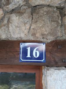 a blue sign with the number on a stone wall at Apartment Vukasevic in Virpazar