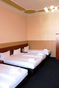 una fila di letti in una stanza con lenzuola bianche di Hotel-Pension Rheingold am Kurfürstendamm a Berlino