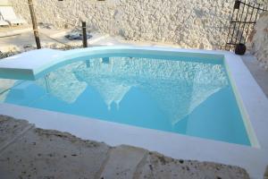 une piscine d'eau bleue en face d'un mur en pierre dans l'établissement Materiis, à Noci