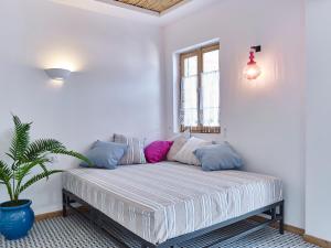 Cama en habitación blanca con maceta en KALITHEA-HILLS APARTMENT 3, en Koskinou